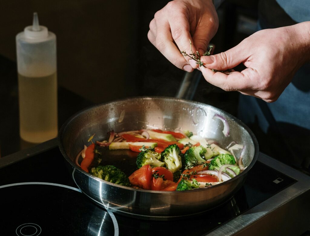 pan with hands above it, the hands are about to put in some sort of spice